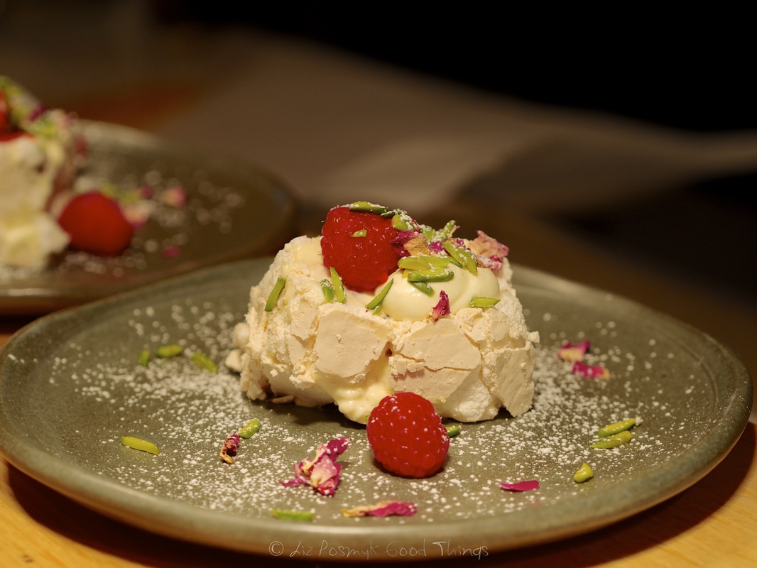 Meringue roulade with raspberries, rose petals and pistachios