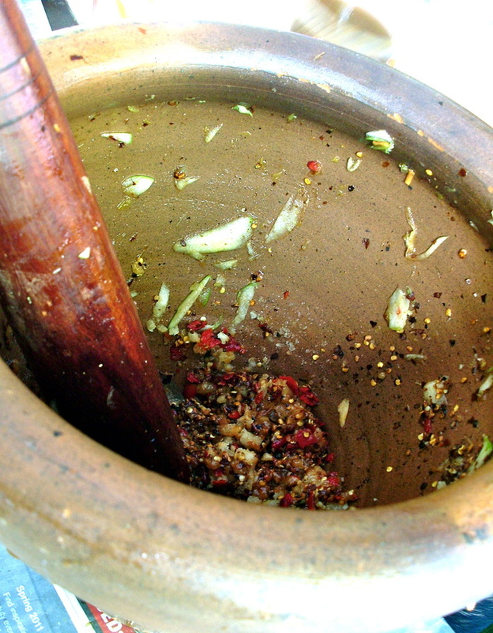 A terracotta mortar and wooden pestle are traditionally used to make Som Tum