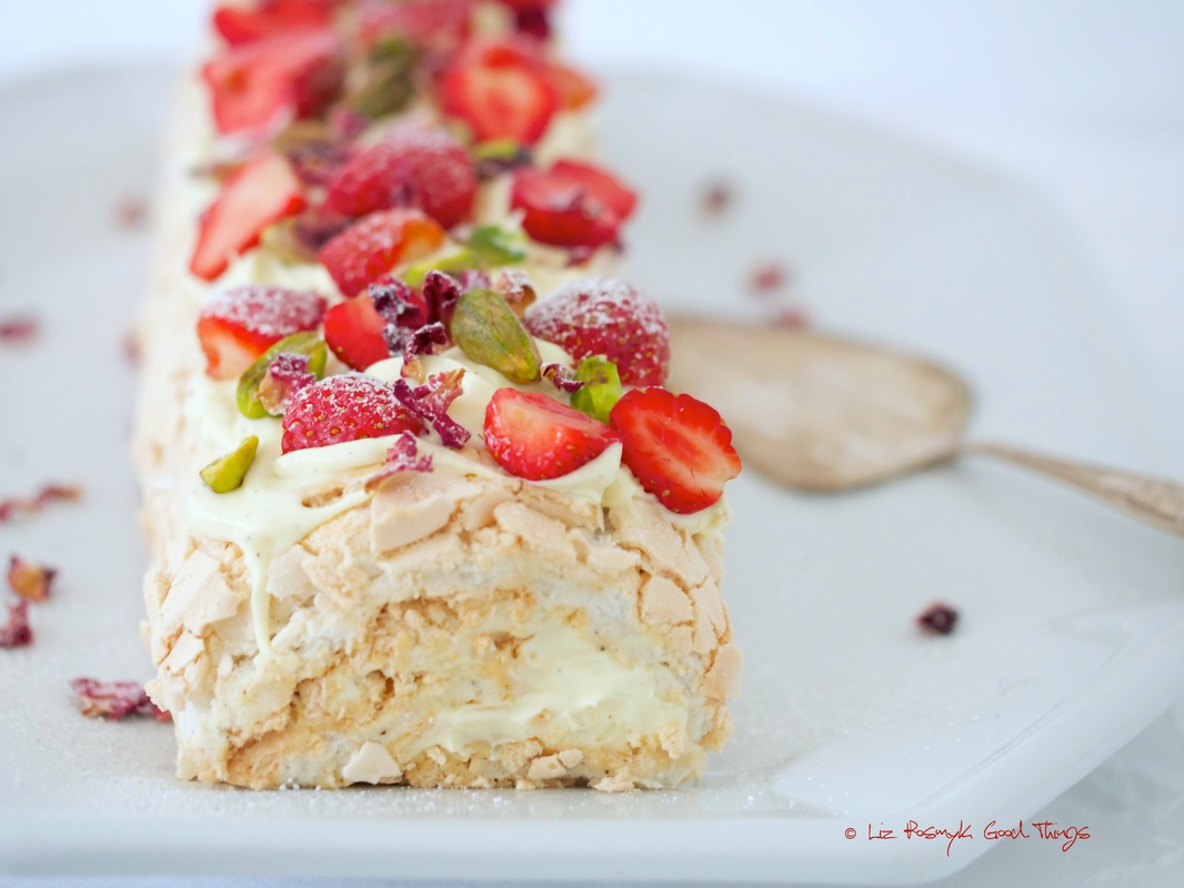 Meringue roulade with fresh berries, pistachios and rose petals
