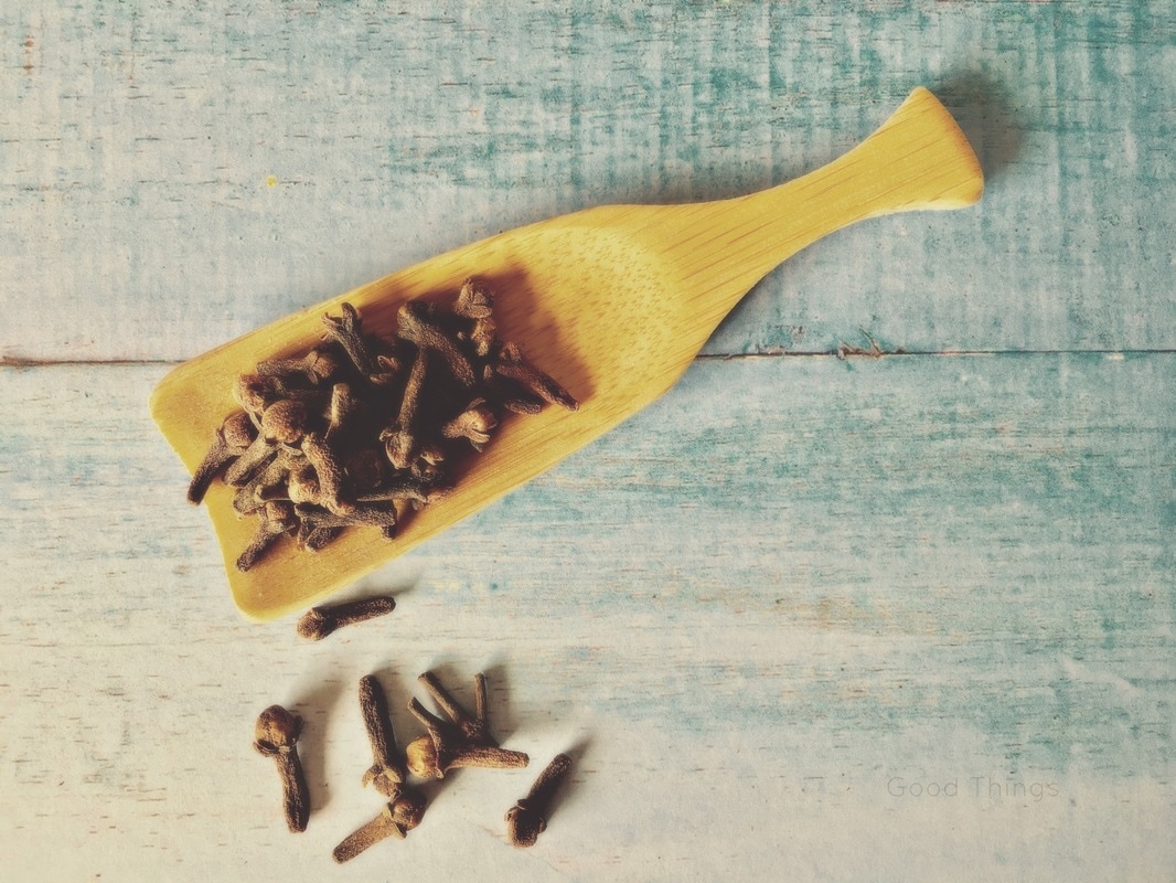 Cloves spilling out of a wooden spoon by Liz Posmyk Good Things
